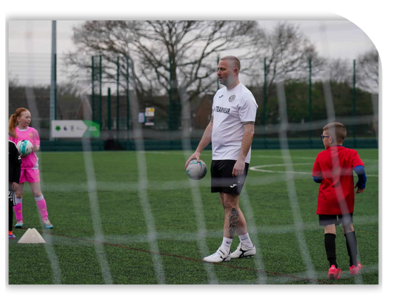 GS Coaching Academy youth soccer team posing with coach on an outdoor field at night